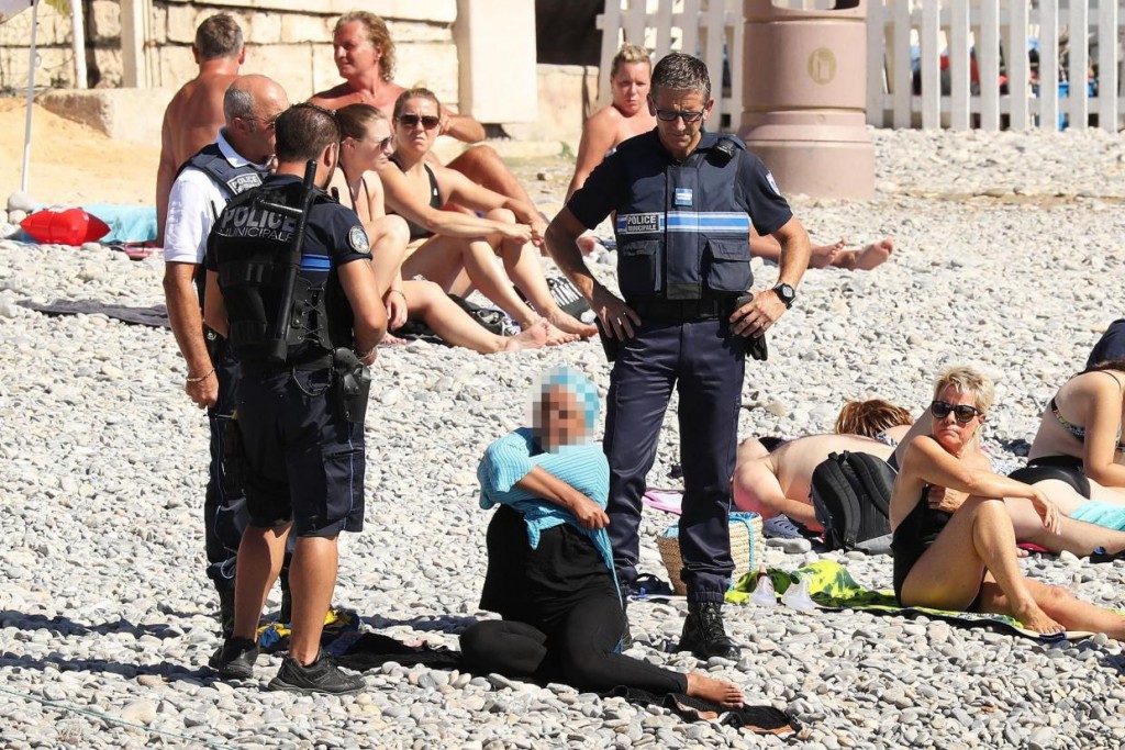 Die Taten von echten (und vermeintlichen) IS Anhängern sollen in den westlichen Gesellschaften Ressentiments gegen Muslime schüren und zu deren Ausgrenzung führen. (Französisch Polizisten setzen an einem Strand das Burkini Verbot durch) / Quelle: The Independent